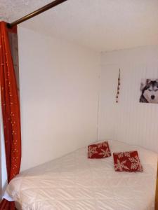 1 dormitorio con 1 cama con 2 almohadas rojas en Appartement chalet en plein centre des Saisies en Hauteluce