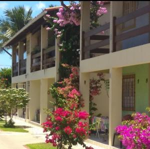 un edificio con flores rosas a su lado en Condomínio Amanda Travassos en Jaguaribe