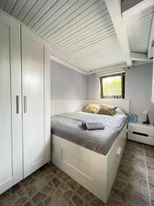 a white bedroom with a bed and a window at Noclegi nad jeziorem w Puszczy Zielonka in Kamińsko