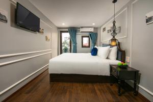 a bedroom with a white bed and a television at La Renta Hotel & Spa in Hanoi