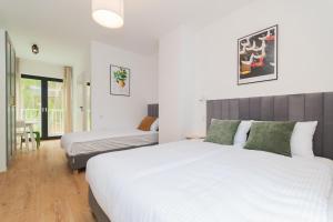 two beds in a bedroom with white walls and wooden floors at uTadka in Sztutowo