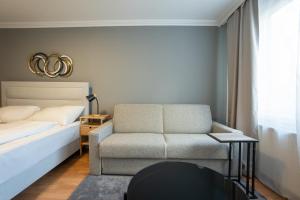 een slaapkamer met een bed, een bank en een stoel bij A spacious 3-bedroom apartment with king-size beds is located within 5 minute’s walk from the Prater in Wenen