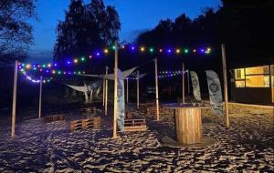een tent met verlichting en een tafel in het zand bij Domek nad jeziorem w Puszczy Zielonka in Kamińsko