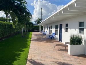 a patio with blue chairs and a white building at 2 Min Walk To The Beach-all Renovated Studio #4 in Fort Lauderdale