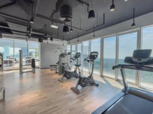 a gym with exercise equipment in a room with windows at The bright One Residence by Suiteable Interiors in Dubai