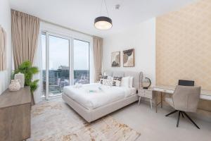 The bright One Residence by Suiteable Interiors في دبي: غرفة نوم بيضاء بها سرير ومكتب ونافذة