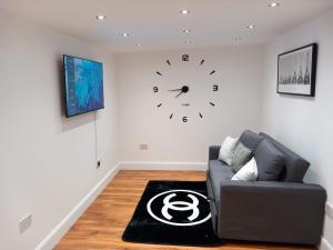 uma sala de estar com um sofá e um relógio na parede em Heronsgate GH013 em Erith