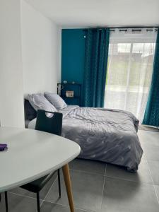 Schlafzimmer mit einem Bett, einem Tisch und einem Fenster in der Unterkunft Blu'in - Mérignies in Mérignies