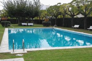 una piscina azul en un parque con bancos en Apartmento Duplex, en S'Agaró