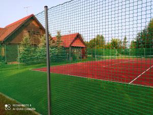 una pista de tenis con una red frente a una casa en Dom z bala z prywatnym kortem i plażą, en Krzywe