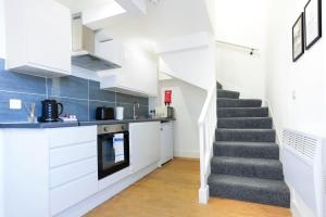 a kitchen with white cabinets and a staircase at Central Buckingham Apartment #8 with Free Parking, Pool Table, Fast Wifi and Smart TV with Netflix by Yoko Property in Buckingham