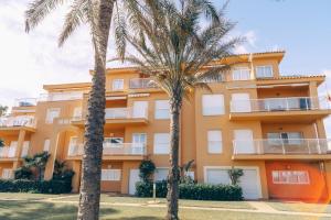 un edificio con palmeras delante en Primera línea, parking, wi fi, apartamento Palm Beach, en Denia
