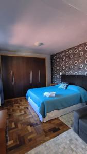 1 dormitorio con 1 cama azul y 1 sofá en Centro de Gramado en Gramado