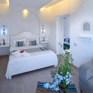 a white bedroom with a large white bed and flowers at Dar Oguz in Ḩammām al Ghazzāz
