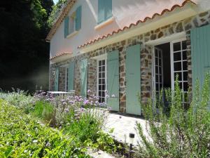 une maison en pierre avec des volets verts et un jardin dans l'établissement Magnifique Maison avec piscine sans vis à vis 4 chambres et 1 mezzanine dans un milieu verdoyant, à Saint-Jean-du-Gard