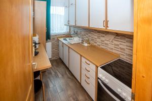 una pequeña cocina con armarios blancos y fregadero en Otthon A Pagonyban, en Mátraszentimre