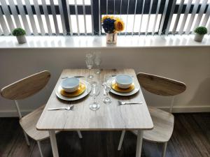 a wooden table with plates and wine glasses on it at Stylish One Bedroom City Centre Apartment with Free Parking in Birmingham