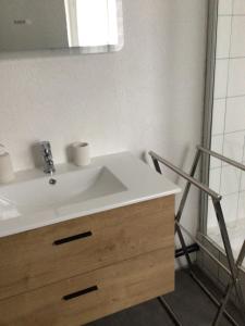 W łazience znajduje się biała umywalka i lustro. w obiekcie Appartement Les Iris w mieście Luz-Saint-Sauveur