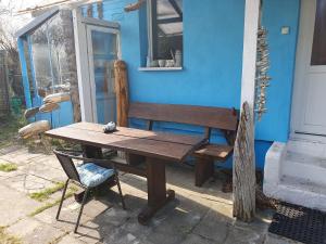 une table en bois et un banc à côté d'une maison bleue dans l'établissement Ferienhaus Dünenhaus, à Dierhagen