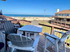 una mesa azul y sillas en una terraza con la playa en Escape OBX, en Kitty Hawk