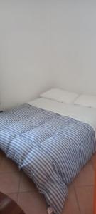 ein weißes Bett mit einer blau-weißen gestreiften Decke in der Unterkunft Agriturismo Borgo Nuovo Sant'Agata dei Goti in Migliara