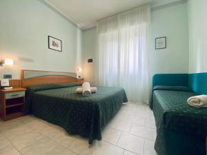 a hotel room with two beds and a window at Hotel Villa Grazia in Cesenatico