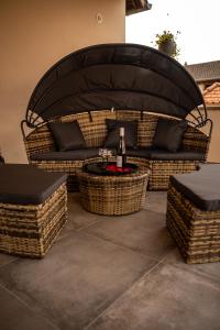 a patio with wicker furniture and a table with a bottle of wine at Love industrie & spa - Suite Romantique en Alsace - Spa privatif et garage in Bischoffsheim