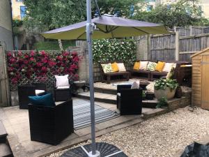 un patio con sombrilla, sofás y sillas en Holloway House, en Bath