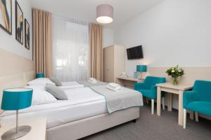 pokój hotelowy z łóżkiem i 2 niebieskimi krzesłami w obiekcie Villa Angela w Gdańsku