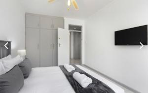 a white room with a bed and a flat screen tv at Beautiful Beachfront apartment in Cape Town