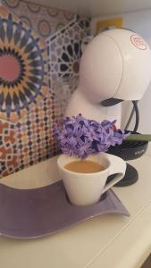 eine Tasse Kaffee und lila Blumen auf der Theke in der Unterkunft Victory in Stara Sagora