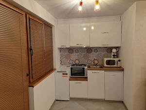 a kitchen with white cabinets and a microwave at Victory in Stara Zagora