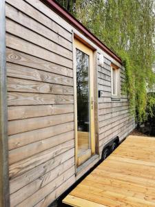 drewniany domek z drzwiami i drewnianym tarasem w obiekcie Schäferwagen Hygge nähe Reuss w mieście Gisikon