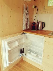 a kitchen with an empty refrigerator with bottles in it at Schäferwagen Hygge nähe Reuss in Gisikon