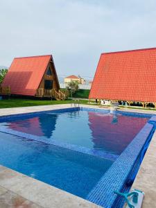 a swimming pool with a red roof and a barn at NOEL BUNGALOV & CAFE in Demre