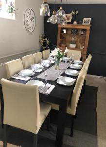 uma mesa de jantar preta com pratos brancos e cadeiras em Holloway House em Bath