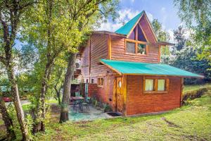 una pequeña casa de madera con techo verde en Cabañas Kairós en El Bolsón