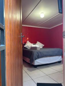 1 dormitorio con cama y pared roja en Grey house lodge, en Pietermaritzburg