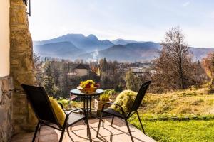ザコパネにあるApartamenty Szymoszkowa Resort Ski Zakopaneの山の景色を望むパティオ(テーブル、椅子付)