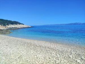 una playa rocosa con agua azul en un día soleado en Smještaj Latis, en Vela Luka