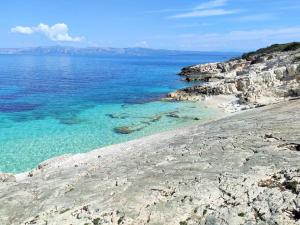 a beach with turquoise water and a rocky shore at Smještaj Latica in Vela Luka