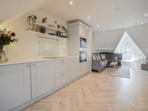 a kitchen with white cabinets and a living room at Fore Street House - Apartment 3 in Seaton