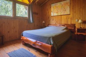um quarto com uma cama num quarto de madeira em Cabañas Kairós em El Bolsón