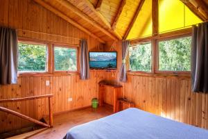 a bedroom with wooden walls and windows and a bed at Cabañas Kairós in El Bolsón