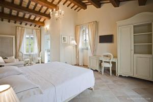 una camera con un grande letto bianco e una scrivania di Borgo Conde Wine Resort a Forlì