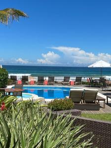 a swimming pool with chairs and the ocean in the background at Maravista Hotel & Spa Ltda in Búzios