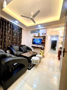 a living room with black leather furniture and a flat screen tv at Airport Bliss Apartment+Balcony & Netflix + Prime in Jaipur