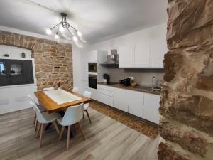 a kitchen with a wooden table and white cabinets at Dommu de Anna Murru in Baunei