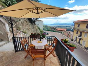 un tavolo e sedie su un balcone con ombrellone di Dommu de Anna Murru a Baunei