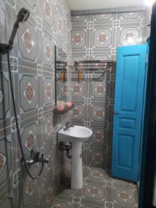 a bathroom with a sink and a blue door at Mina Café & Stay in Quan Lạn